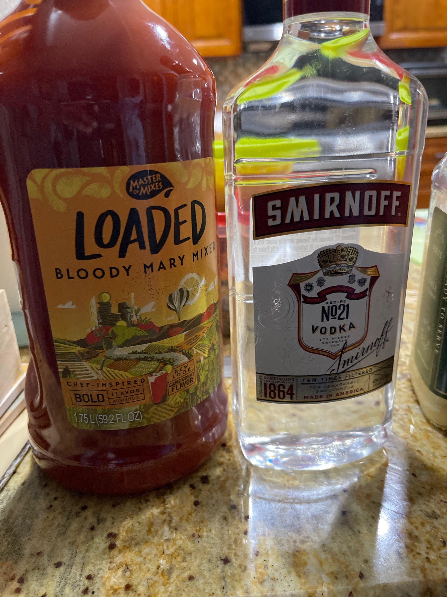social lubricants: bloody mary mix and vodka sitting on a granite countertop in a kitchen